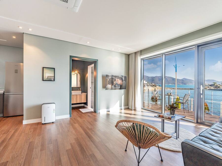 Un espacio habitable moderno con cocina, comedor y un balcón con vistas al mar.