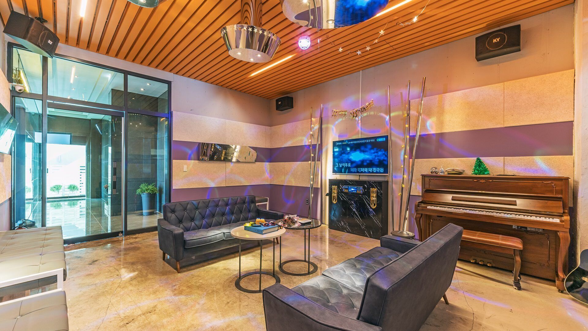Uma sala de estar moderna com sofá, poltronas, mesa de centro, piano e tela de televisão.