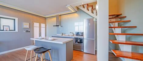 Una cocina moderna con una isla central, estufa integrada y refrigerador de acero inoxidable.