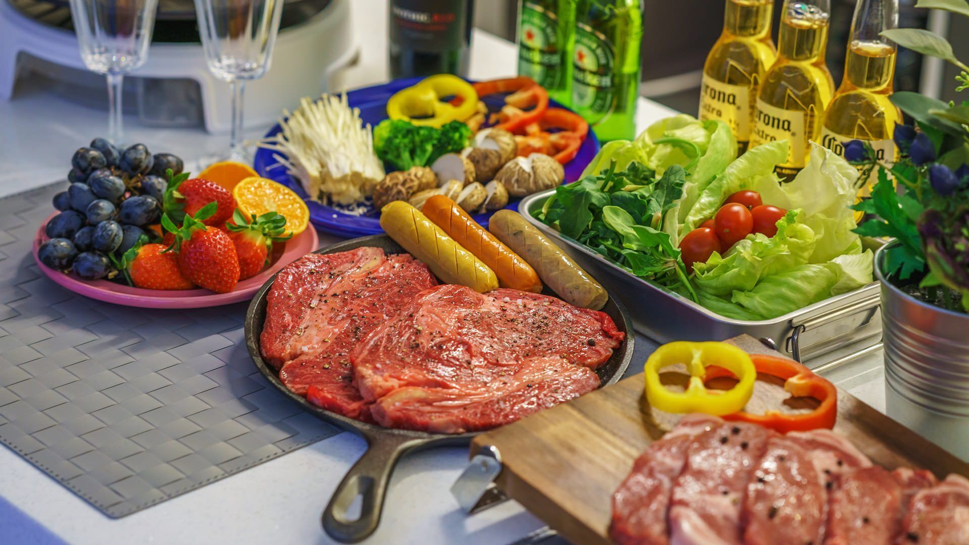 Una mesa con carne cruda, verduras y salsas.