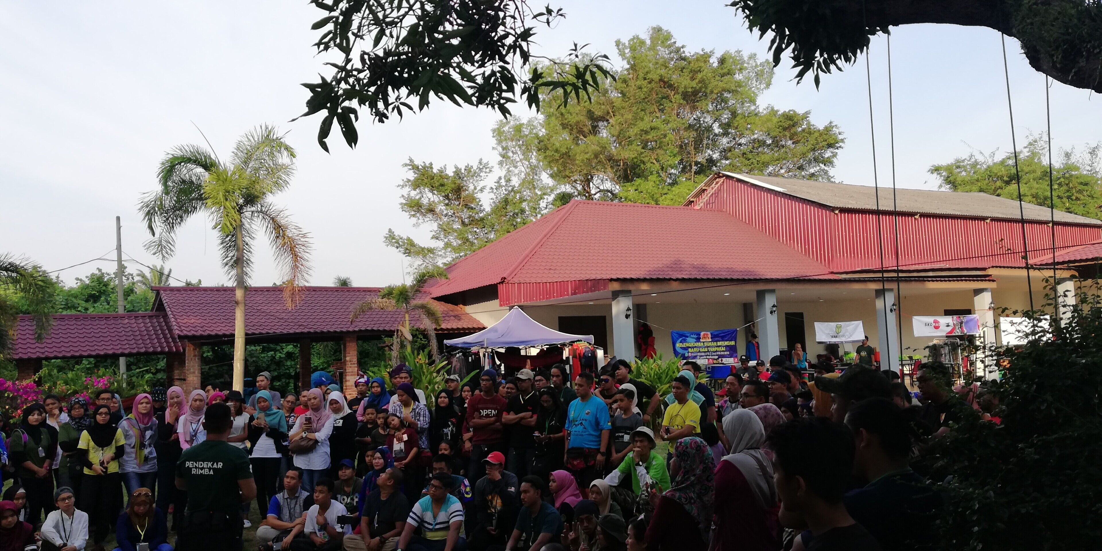 A crowded outdoor event with people gathered around a building with a red roof.