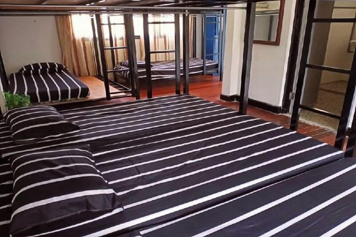 Una habitación con una cama grande, una mesita pequeña y una silla.