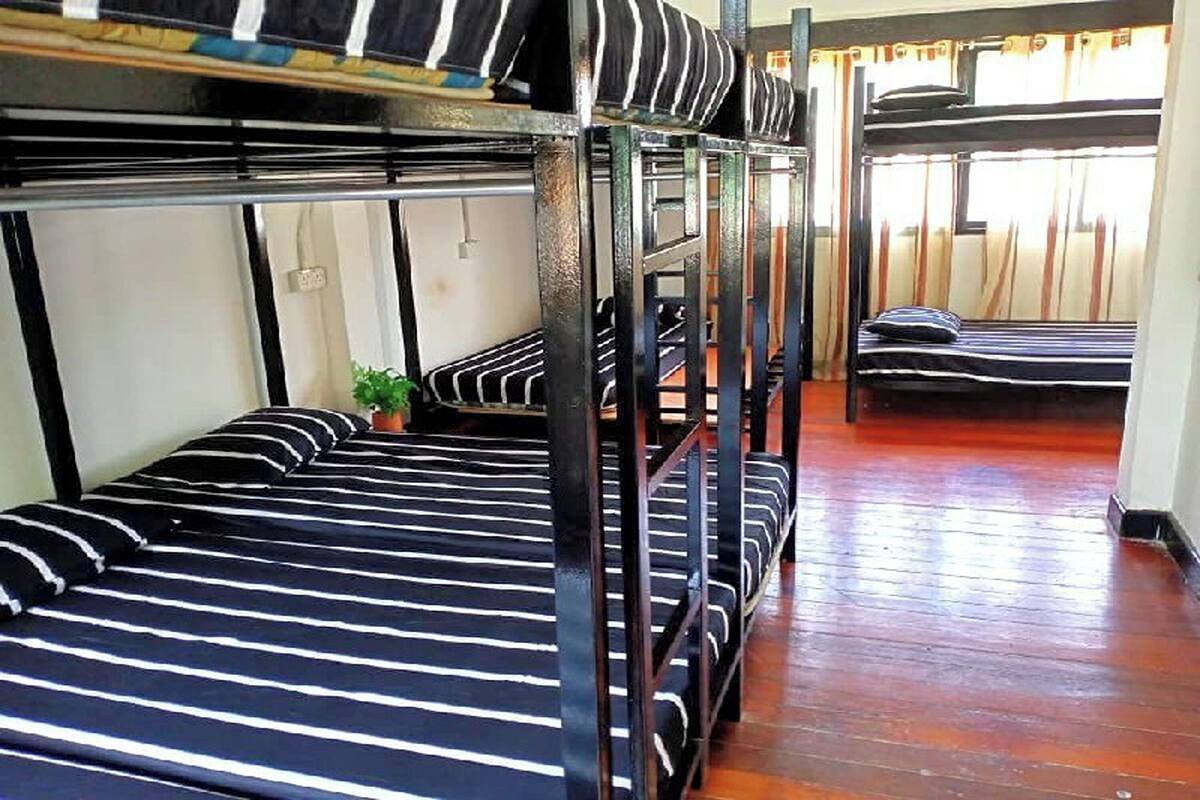 A bunk bed room with striped bedding and wooden flooring.