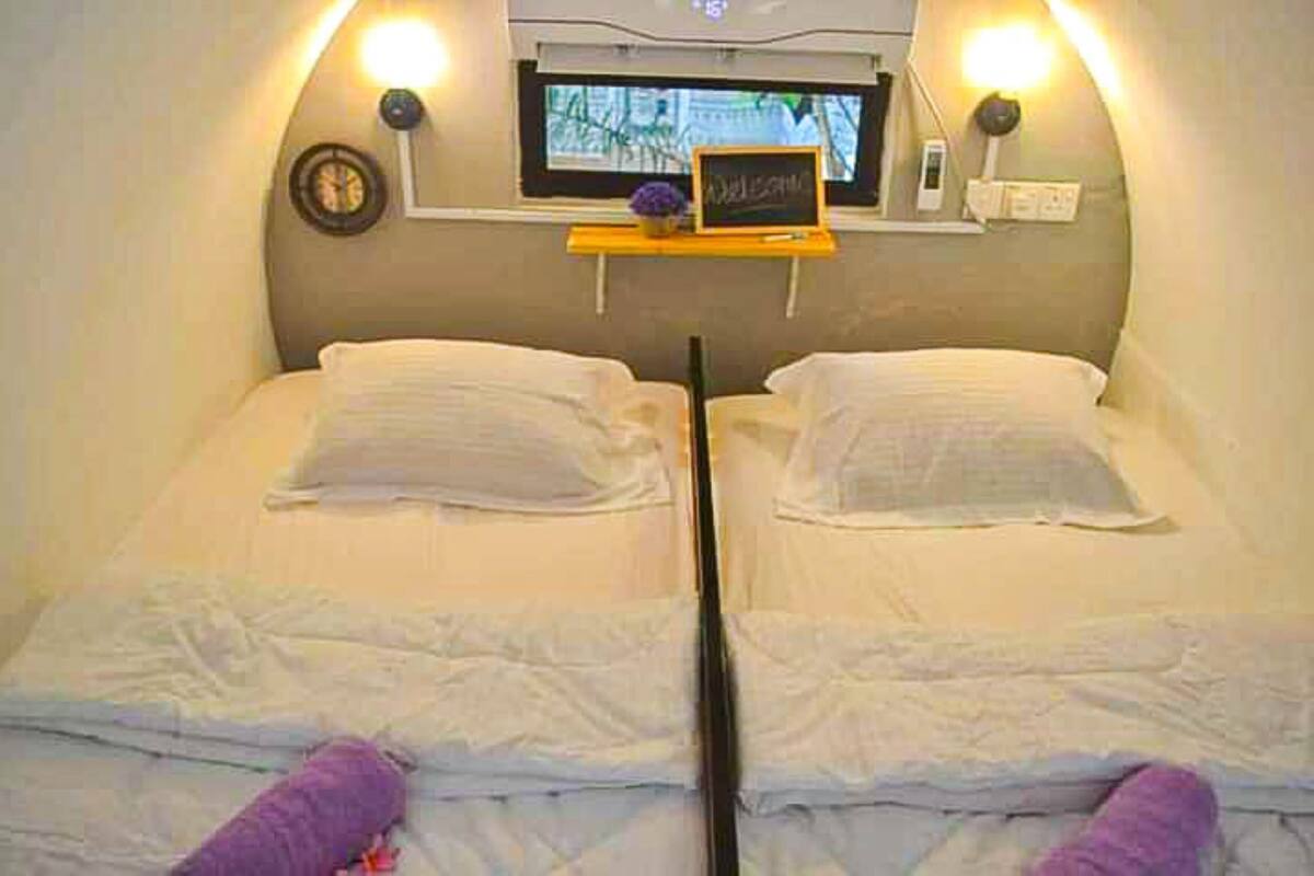 A room with two beds, a small table with a sign, and a window with a view.