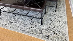 A dining area with a wooden table, leather benches, and a patterned rug.