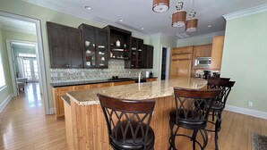 A kitchen with dark wood cabinets, a granite countertop, and a central island with bar stools.