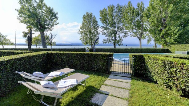 A poolside area with lounge chairs and a view of the sea. - My Lakeside Dream (Sirmione)