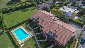 An aerial view of a residential property with a swimming pool, a covered patio, and a well-maintained lawn. - My Lakeside Dream (Sirmione)
