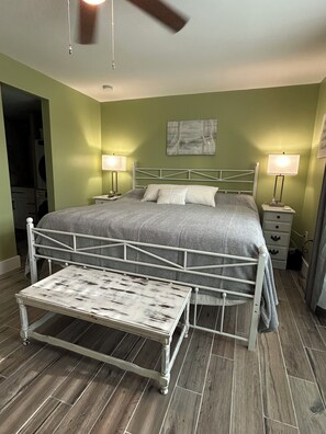 A bedroom with a bed, bedside tables, a ceiling fan, and a small table. - Home Away from Home Beach Getaway Condo (Madeira Beach)