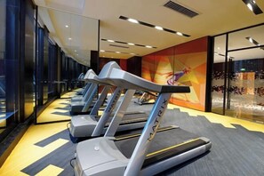 A row of treadmills in a gym with a mirrored wall and a colorful abstract mural in the background. - Hampton by Hilton Guiyang Yunyan Fountain (GUIYANG)