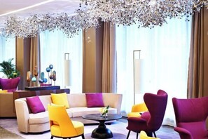 A modern hotel lobby with a beige sofa, yellow and purple armchairs, and a round coffee table. - Hampton by Hilton Guiyang Yunyan Fountain Pool (GUIYANG)