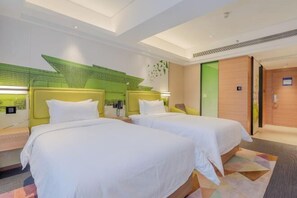 A hotel room with two beds, a green accent wall, and a wooden door. - Hampton by Hilton Guiyang Yunyan Fountain (GUIYANG)
