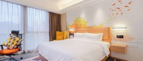 A hotel room with a large bed, a chair, a desk, and a wall with a decorative mural.