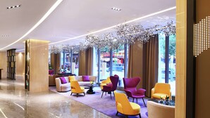 En moderne lobby med en sofa, stole og et sofabord. Store vinduer og udsigt til gaden.