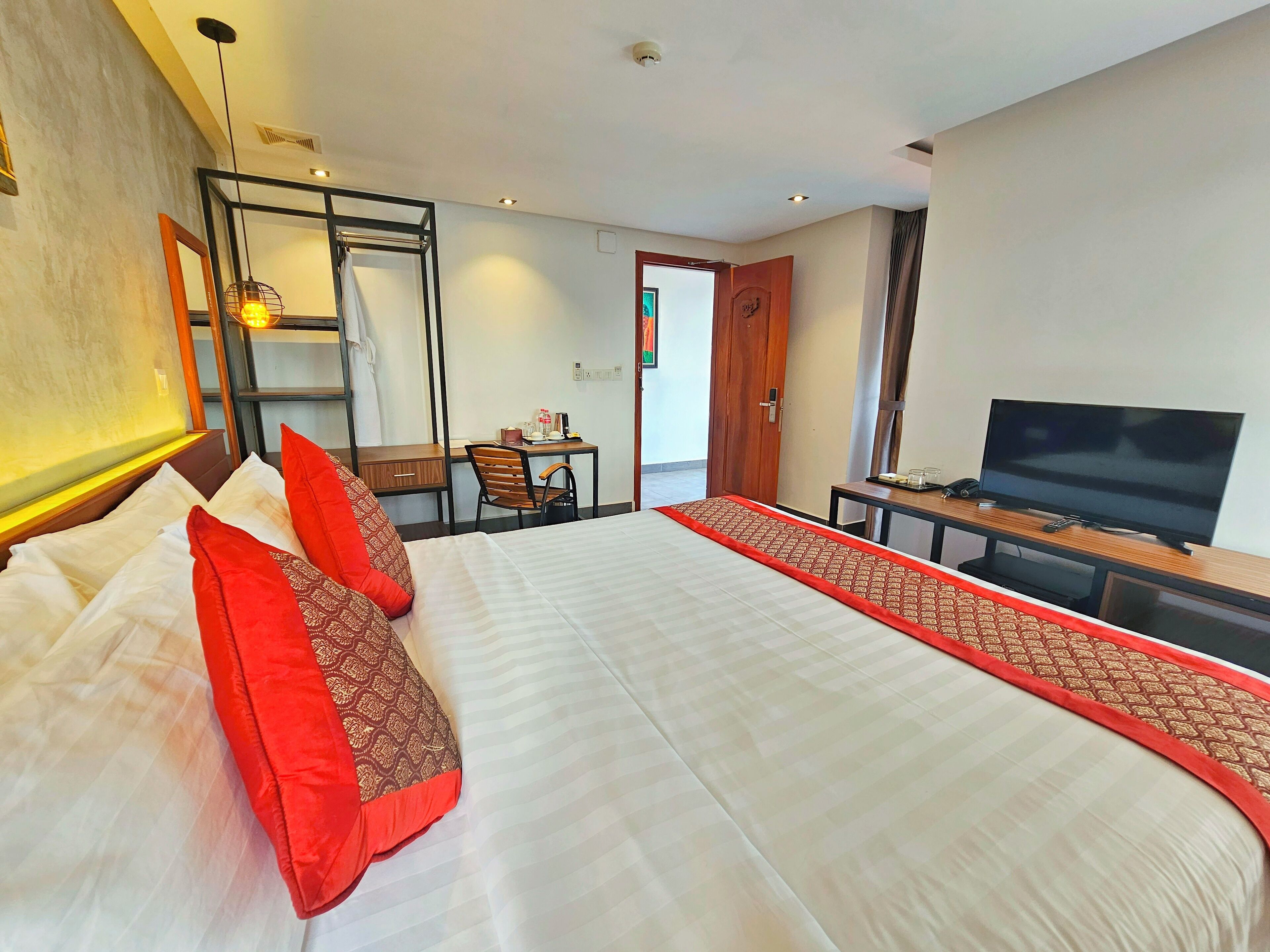 A hotel room with a large bed, a desk with a television, and a chair.