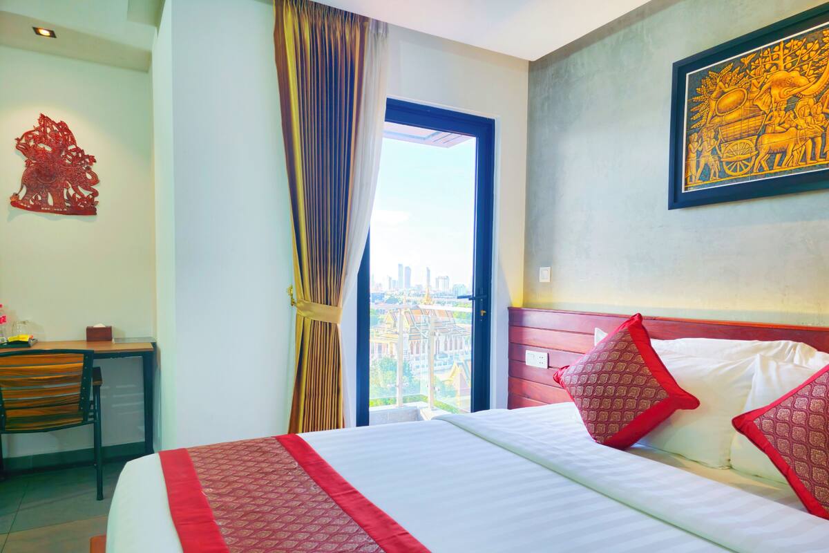 Quarto de hotel com cama, escrivaninha e vista para a cidade.