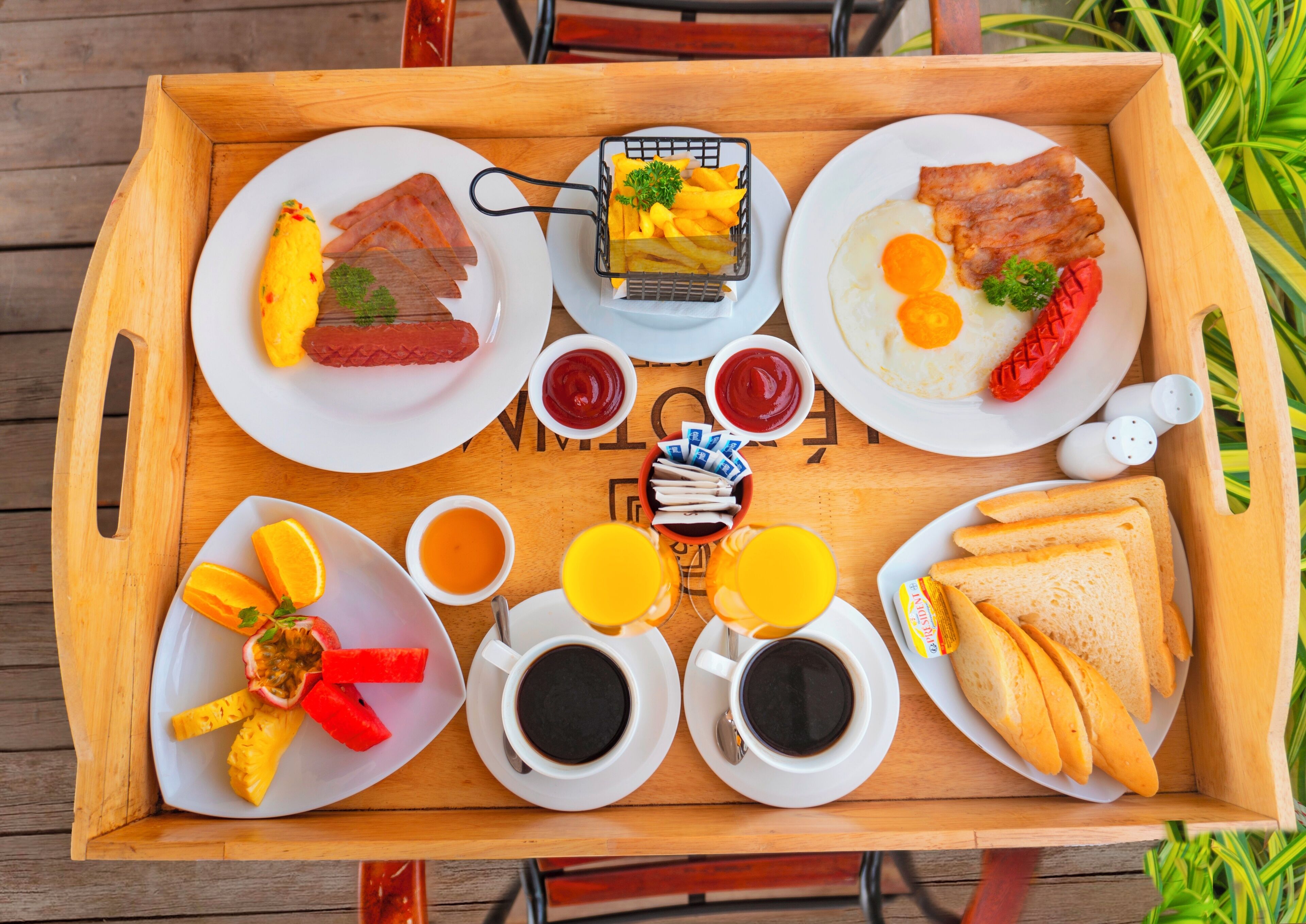 Bandeja de desayuno con huevos, tocino, tostadas, fruta y bebidas.