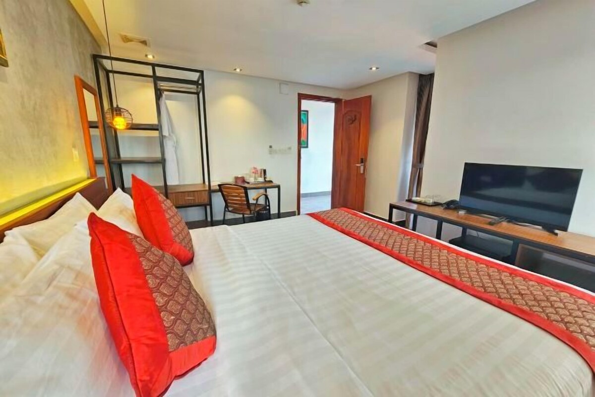 Une chambre d’hôtel avec un grand lit, une télévision, un bureau et une chaise.