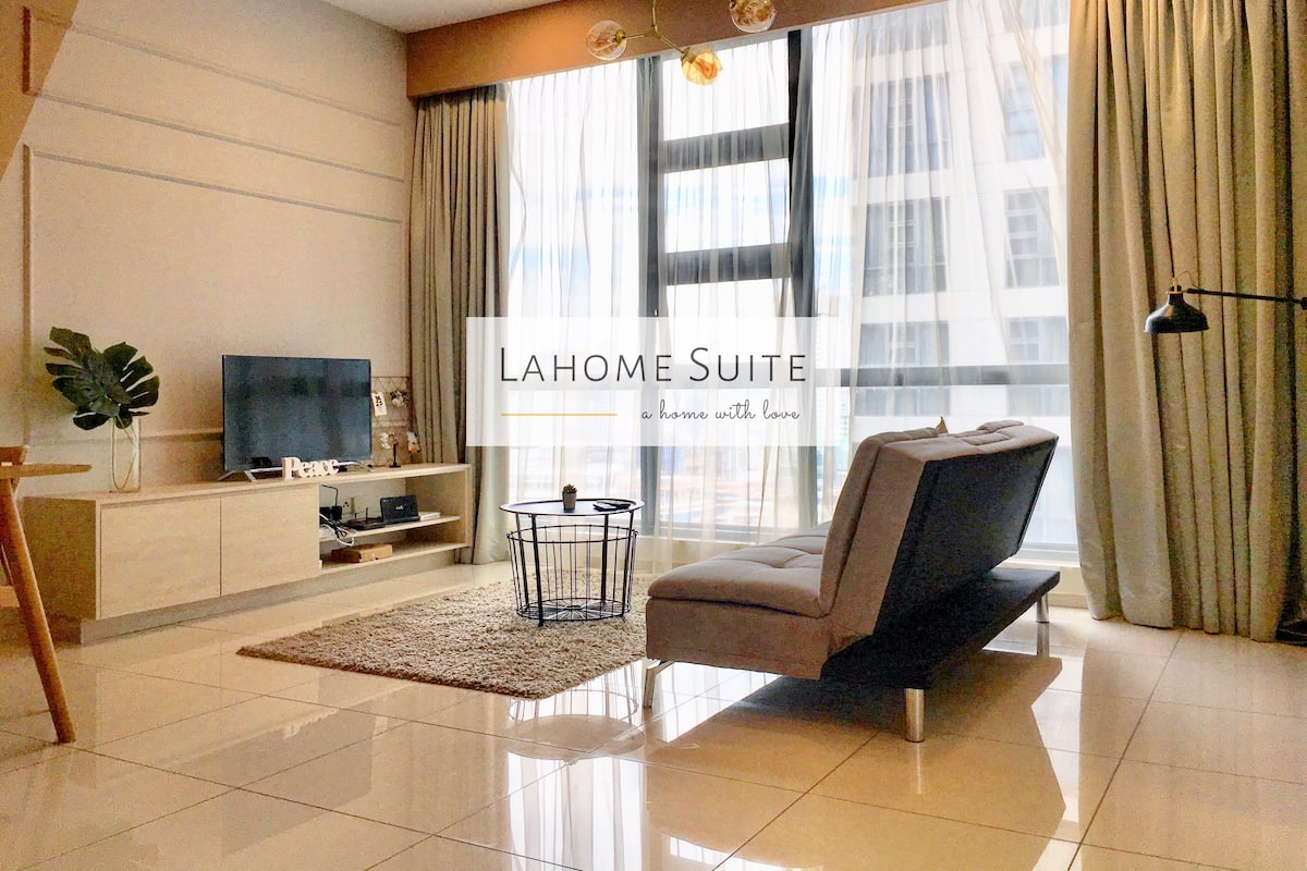 A modern living room with a flat-screen TV, a sofa, a coffee table, and a potted plant.