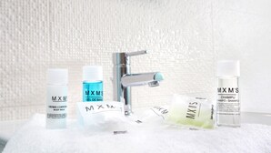 A bathroom with a white tiled wall, a chrome faucet, and various toiletries including body milk, gel, shampoo, and soap. - Stupendo Airport Studio 1 (Lisboa)