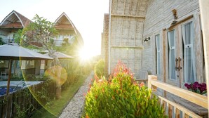 A traditional wooden house with a balcony, a small garden with colorful flowers, and a wooden fence. - Unicorn Bungalow (Penida Island)