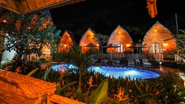 A resort with thatched-roof cottages, a pool, and outdoor seating. - Unicorn Bungalow (Penida Island)