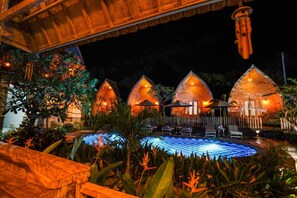 A resort with thatched-roof cottages, a pool, and outdoor seating. - Unicorn Bungalow (Penida Island)