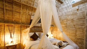 A room with a bed under a canopy, wooden walls, and a nightstand with a lamp. - Unicorn Bungalow (Penida Island)