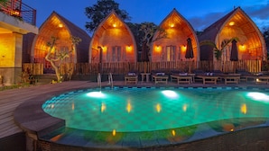A poolside area with wooden cabanas, a checkered pool, and lounge chairs. - Unicorn Bungalow (Penida Island)
