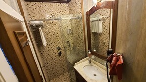 Un bagno con doccia, lavandino, specchio e porta asciugamani.
