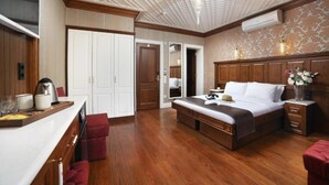 A bedroom with a wooden bed, a desk with a chair, a wardrobe, and a ceiling with a grid pattern.