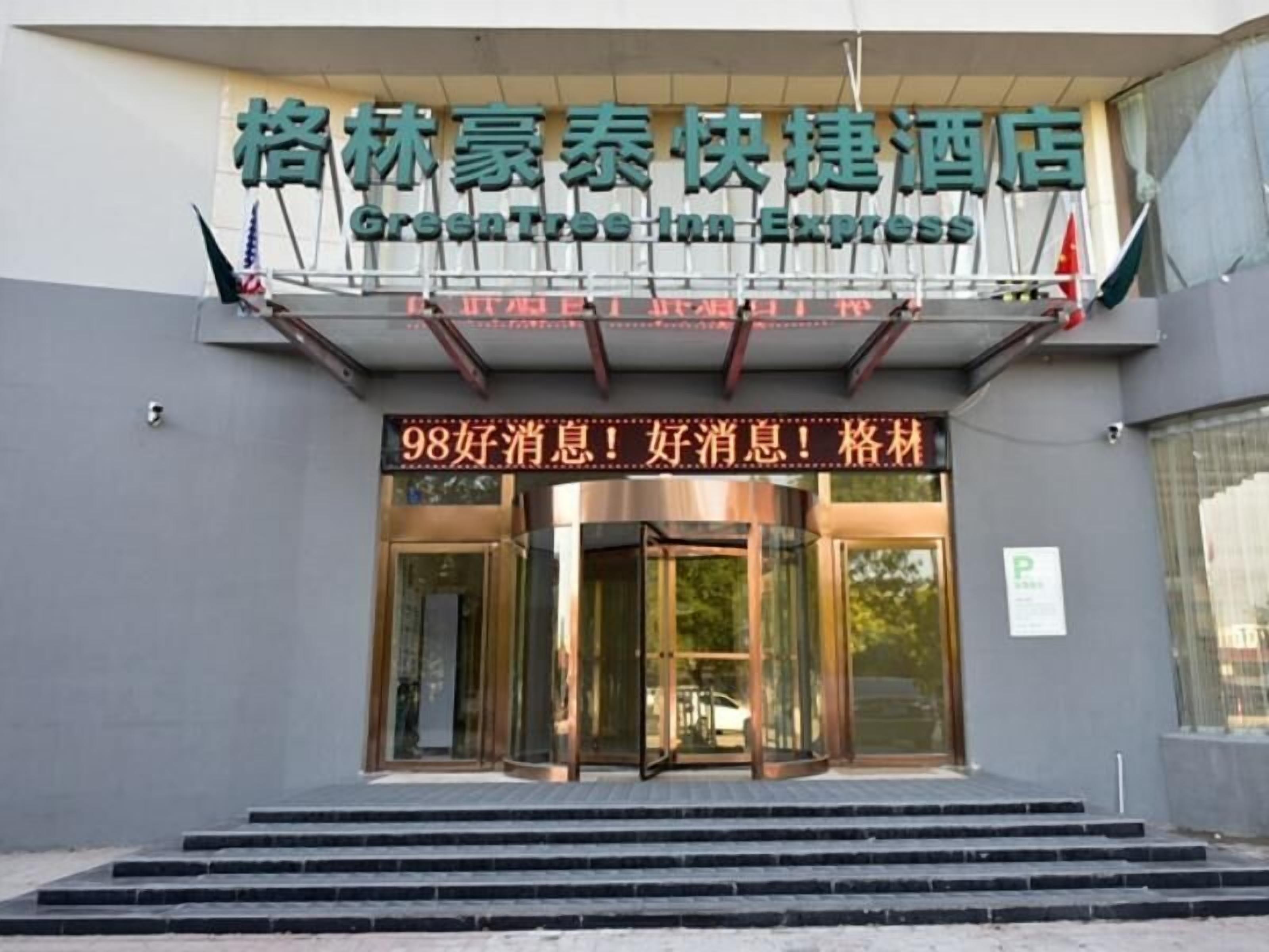 A hotel entrance with a sign in both Chinese and English, a revolving door, and a set of steps leading up to the entrance.