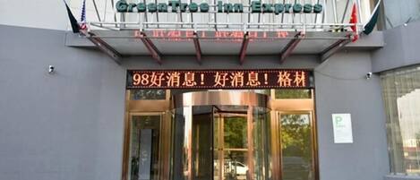 A hotel entrance with a sign in both Chinese and English, a revolving door, and a set of steps leading up to the entrance.