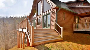 Una cabaña de madera con un balcón y escaleras que llevan a la entrada.