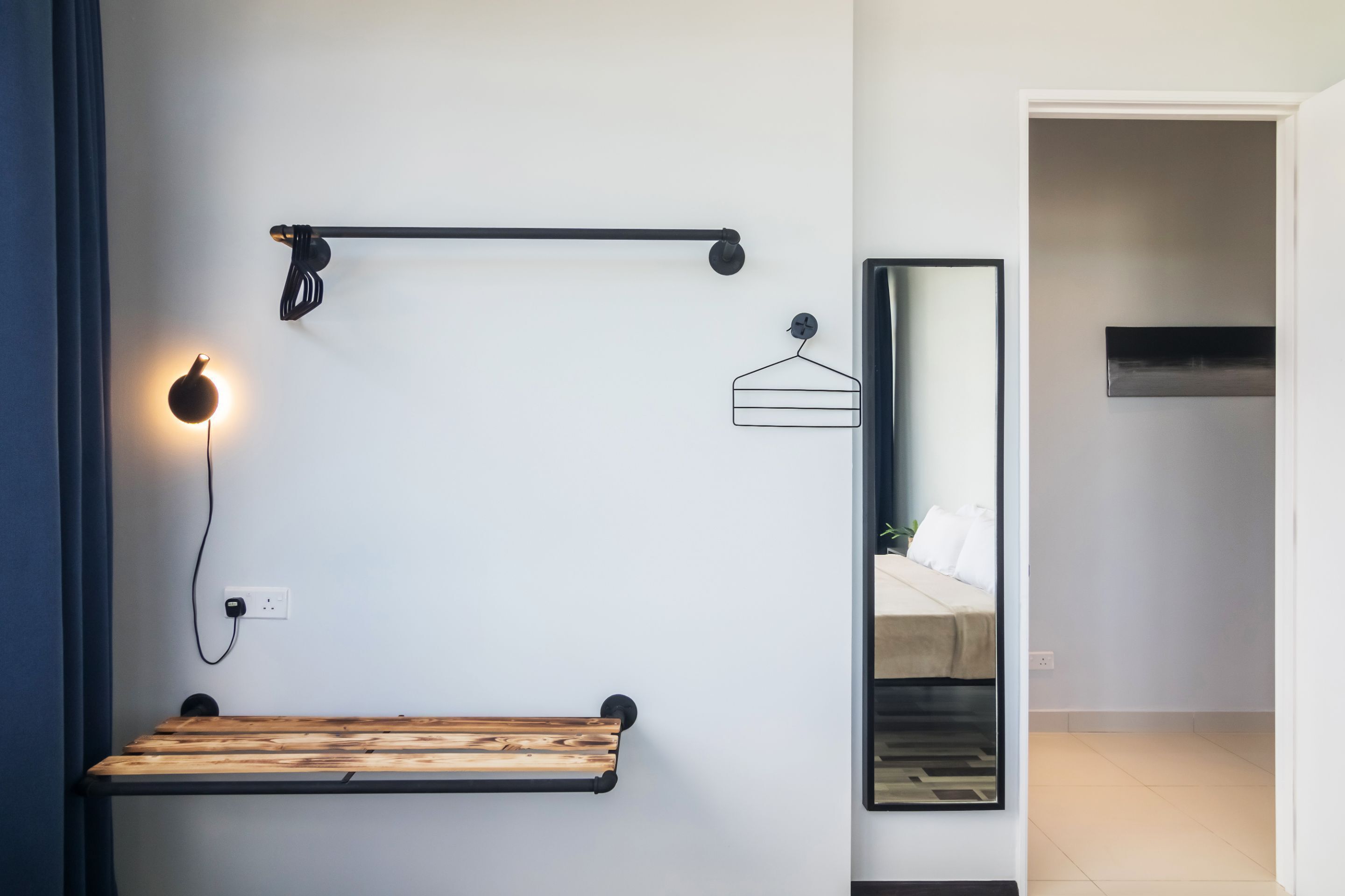 Une salle de bain moderne avec un banc en bois, un porte-serviettes, une serviette suspendue et un miroir.