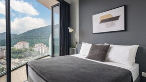 A modern hotel room with a large bed, a view of the city, and a framed artwork on the wall. - Arte S Family Suites (George Town)