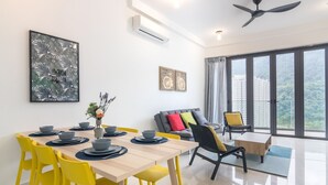 A modern living room with a dining area, large windows, and a view of a cityscape. - Arte S Family Suites (George Town)