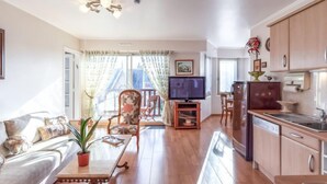 A spacious living room with a sofa, a coffee table, and a TV. There is a kitchen area with cabinets and a refrigerator. - Apartment Le Hoc by Interhome (Deauville-Trouville)
