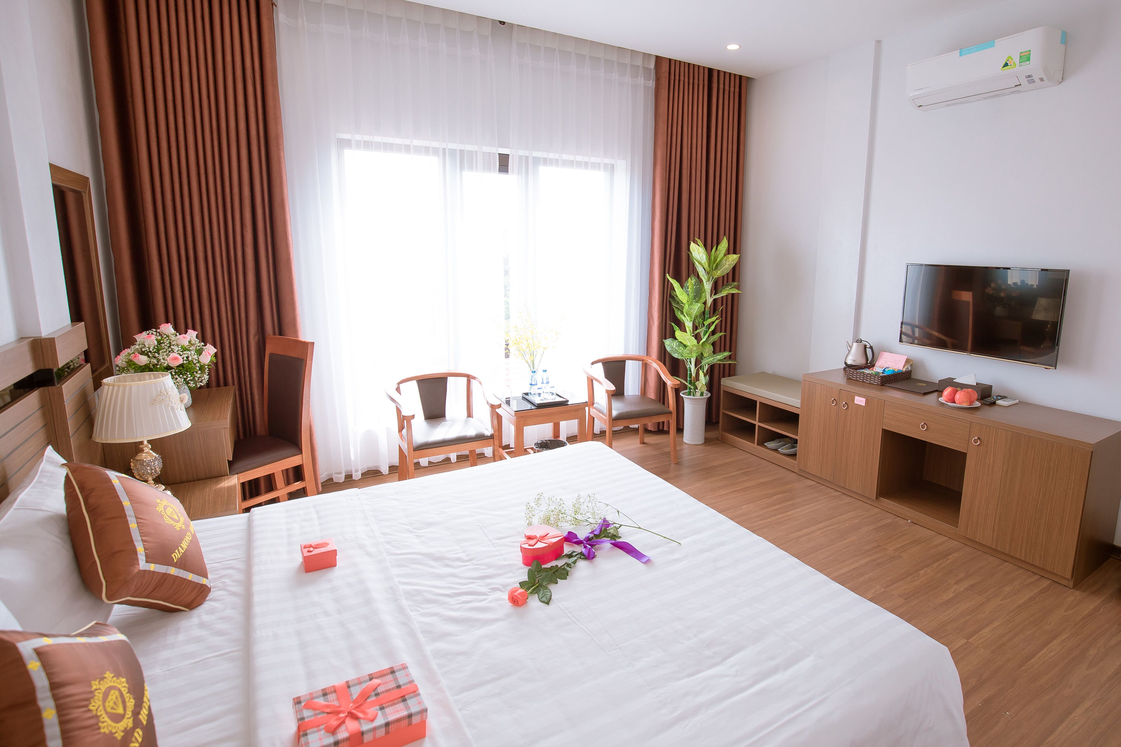 A hotel room with a bed, a desk, a TV, and a window with curtains.