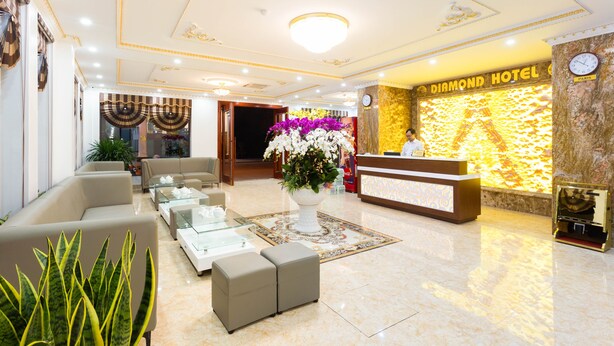 A hotel lobby with a reception desk, seating area, and a large floral centerpiece. - Diamond Hotel (Ninh Binh)