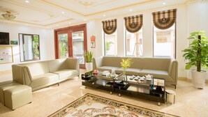 A modern living room with a beige sofa, a glass coffee table, and a decorative rug. - Diamond Hotel (Ninh Binh)