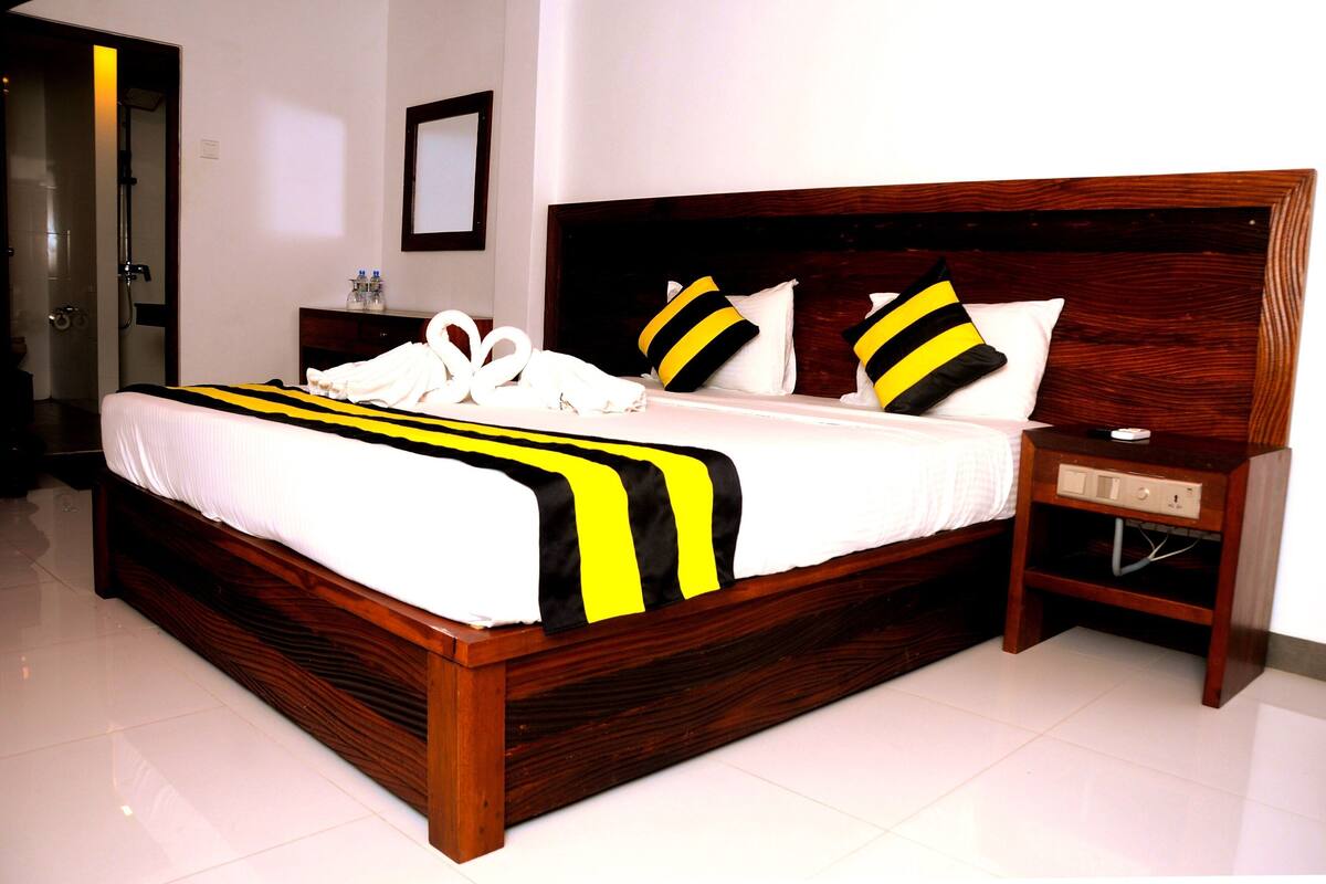 A neatly made bed with a striped bedspread, a wooden headboard, and a bedside table with a lamp.