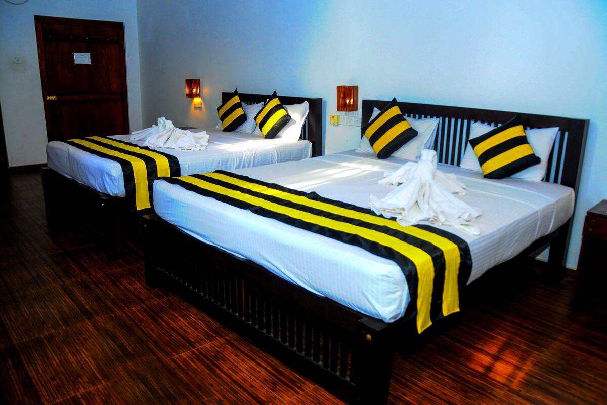 Two beds with black and yellow striped bedspreads, a wooden floor, and a wooden door.