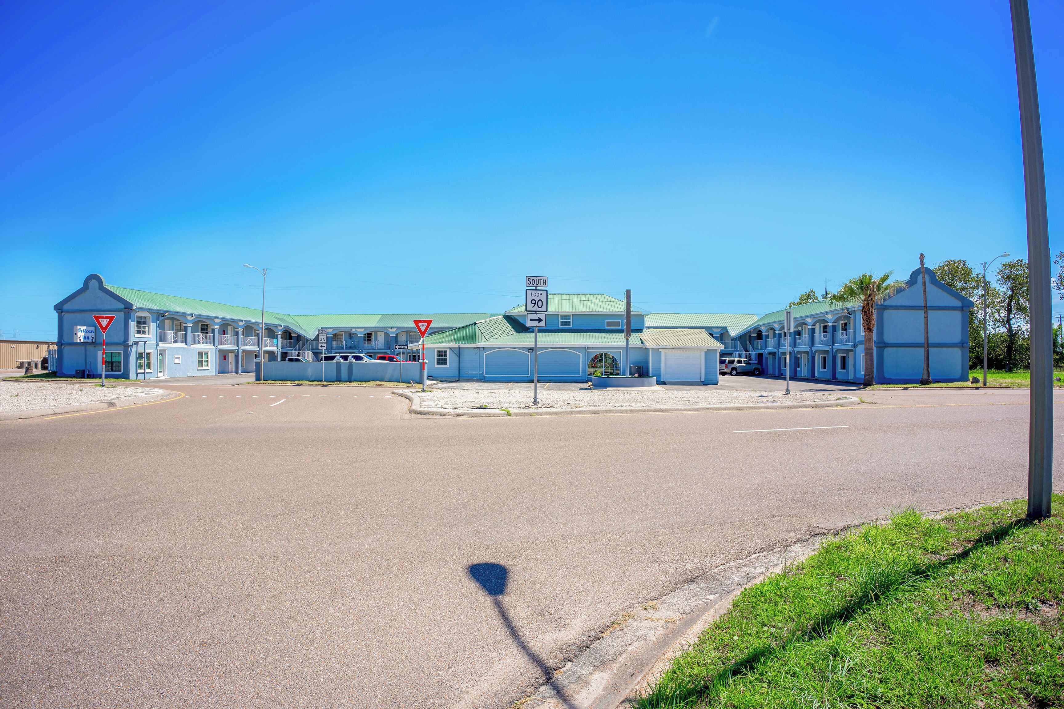 A building with a green roof, multiple windows, and a sign indicating 'South Loop 90'.