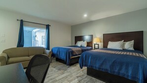 A hotel room with two beds, a sofa, a desk, and a chair.