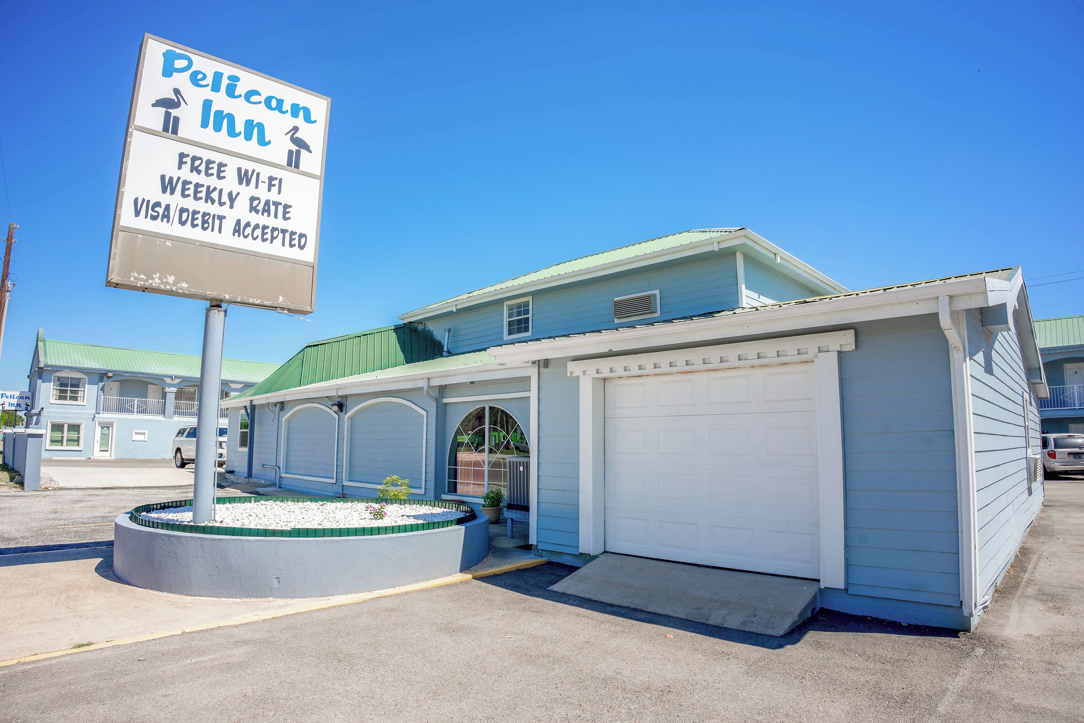 Un motel avec une enseigne indiquant que le Wi-Fi est gratuit, qu’il propose des tarifs hebdomadaires et qu’il accepte les cartes Visa et de débit.