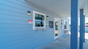 A building with a blue exterior, a 'No Smoking' sign, a window with a 'Please' sign, and a door with a 'Ring Bell For Service' sign.