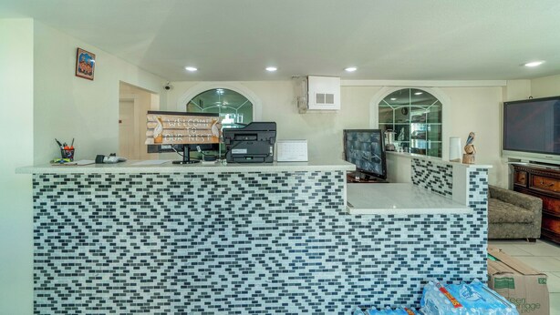 A modern kitchen with a tiled backsplash, a built-in stove, and a large flat-screen TV.
