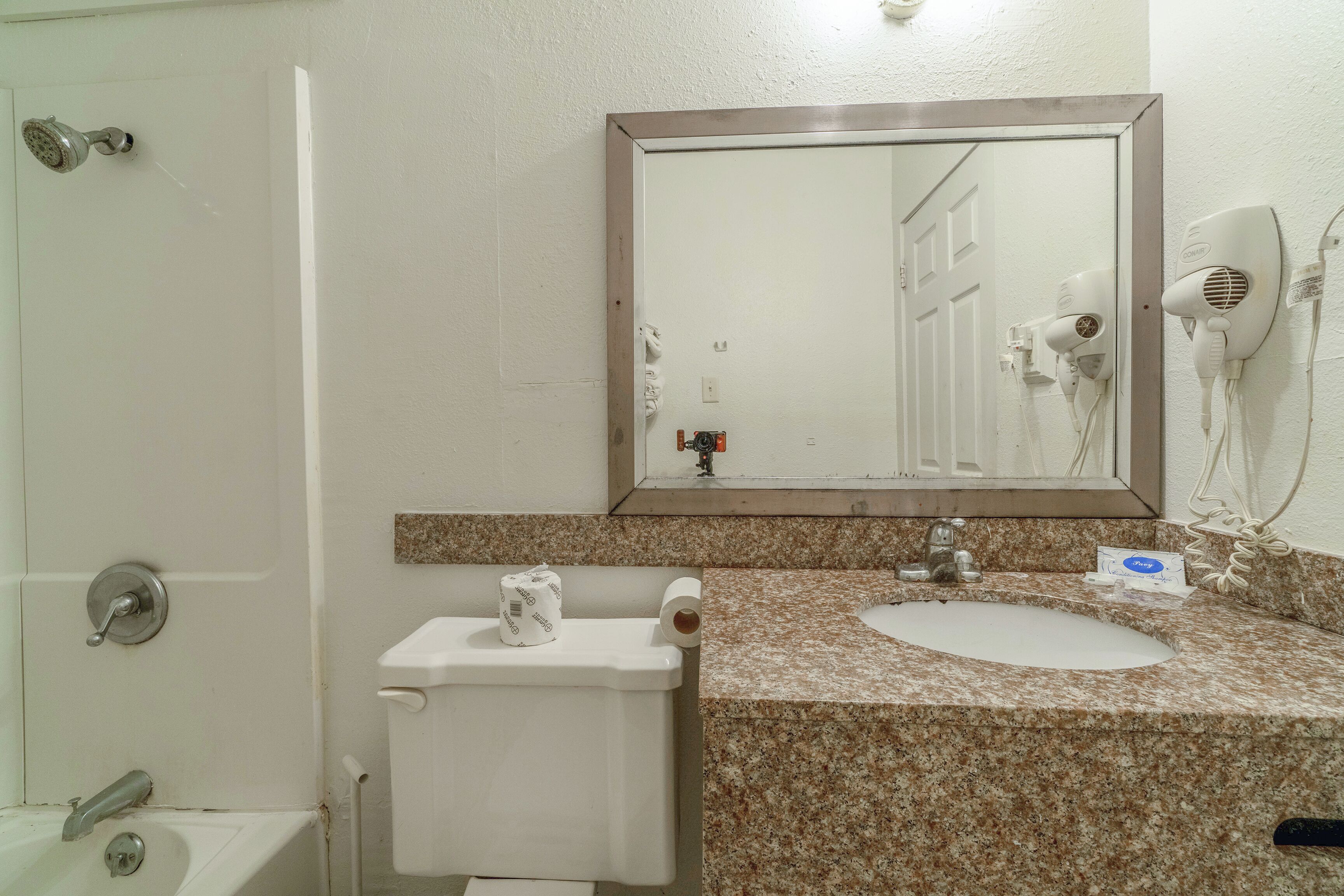 A bathroom with a toilet, sink, and mirror.