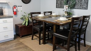 A dining area with a wooden table, dark chairs, and a clock on the wall. - Wonderful 3BDR Guest Suite Sits Between Downtown and the Beach (Charleston)